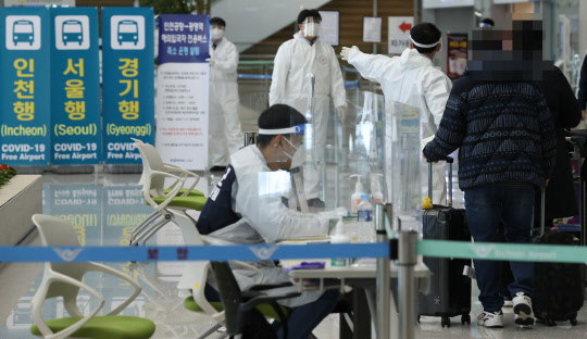 30일 오후 인천국제공항 제2여객터미널 입국장에서 일본 오사카발 항공편 해외입국자들이 방역 관계자들의 안내를 받고 있다. 연합뉴스